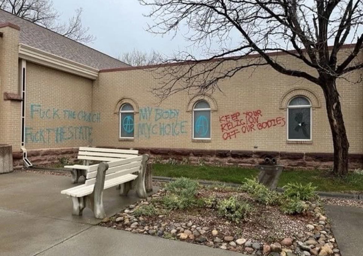 tags sur les murs de l'église : "Fuck the Church, Fuck the State", deux A-entourés, "My Body, My Choice", "Keep your religion off our bodies"